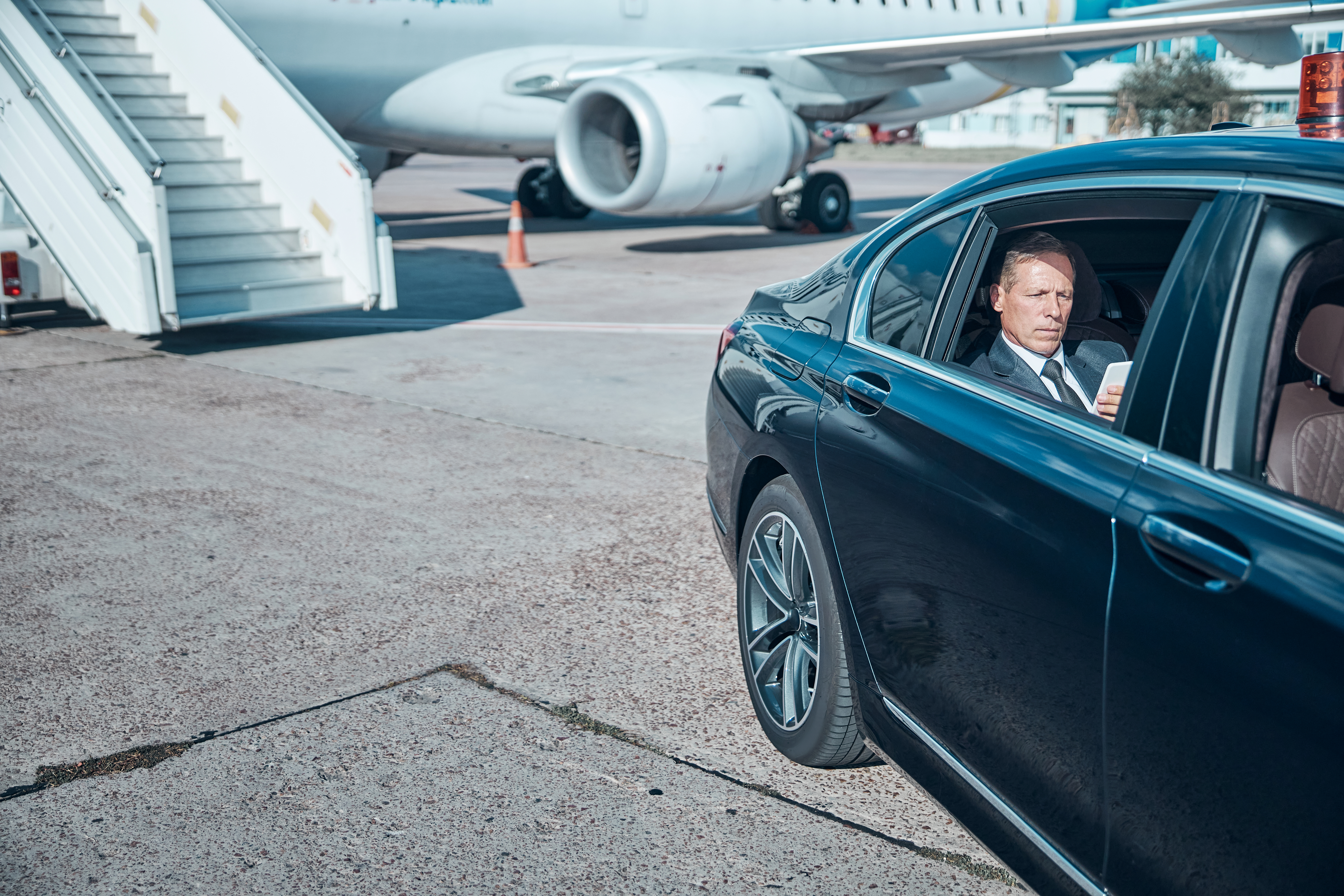 Businessman with smartphone in car at airport - Safe Travels VIP